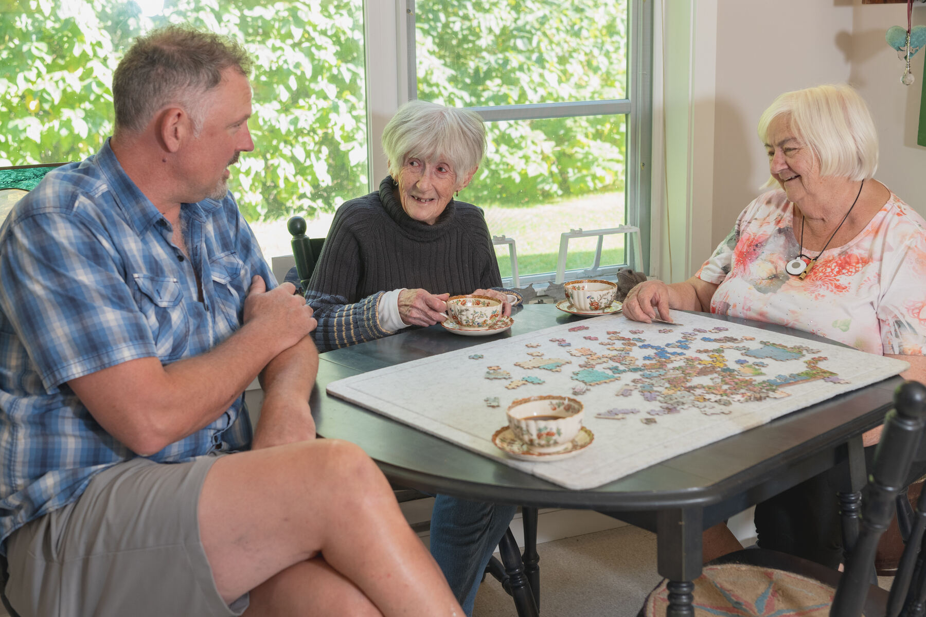 An Evergreen provider doing a jigsaw puzzle with two women at their kitchen table